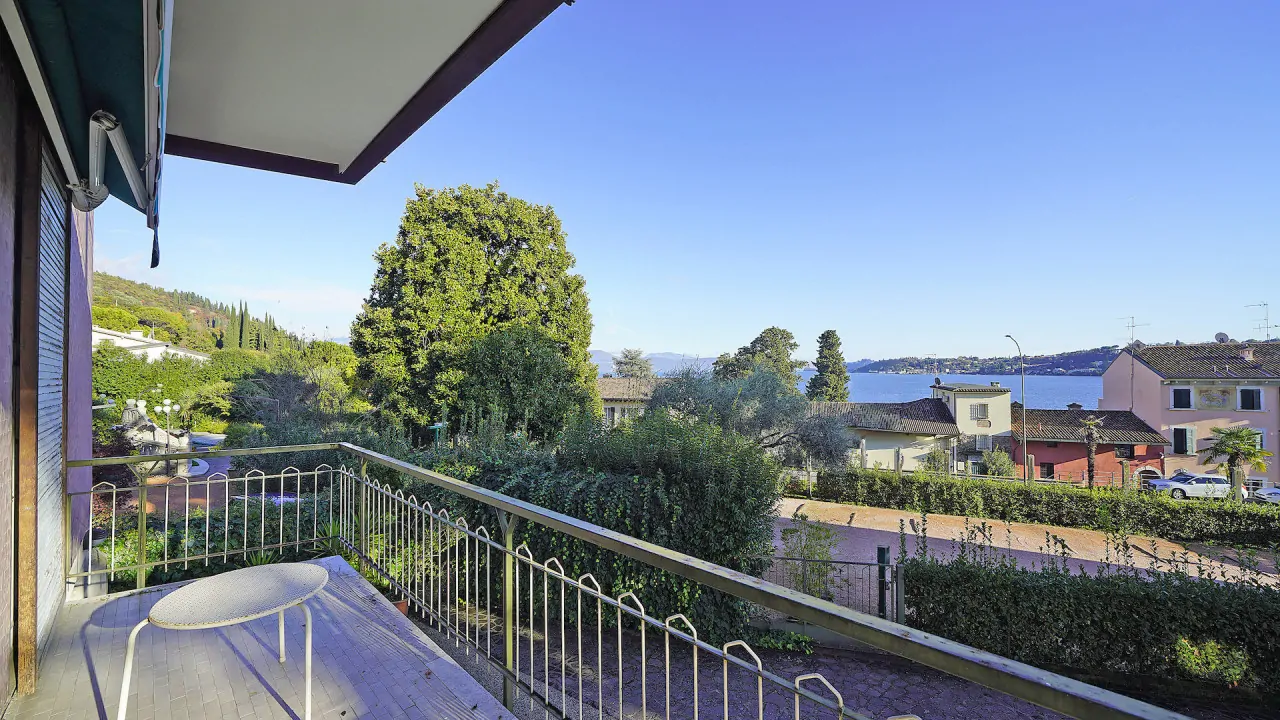 Balcone con ringhiera e vista sul lago e vegetazione