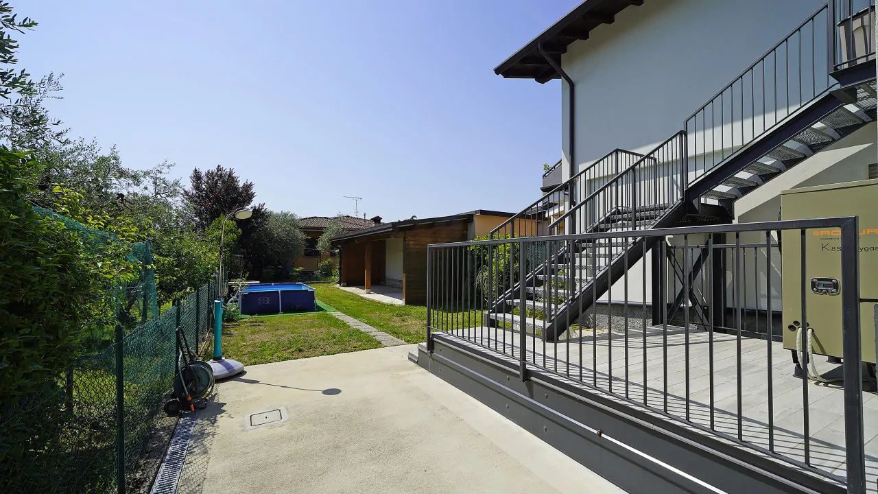 Esterno con scala metallica e giardino con piscina fuori terra