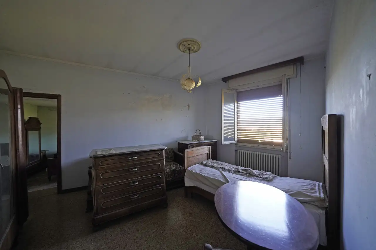 Bedroom with single bed, chest of drawers and open window with lowered shutter