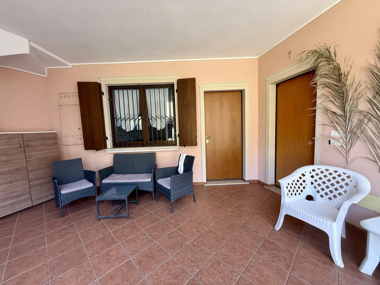 Veranda mit Sitzgelegenheiten und zwei Holztüren