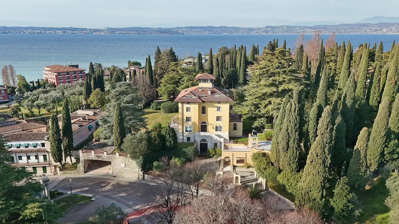 Aerial view of the historic villa with garden and tall trees near the lake