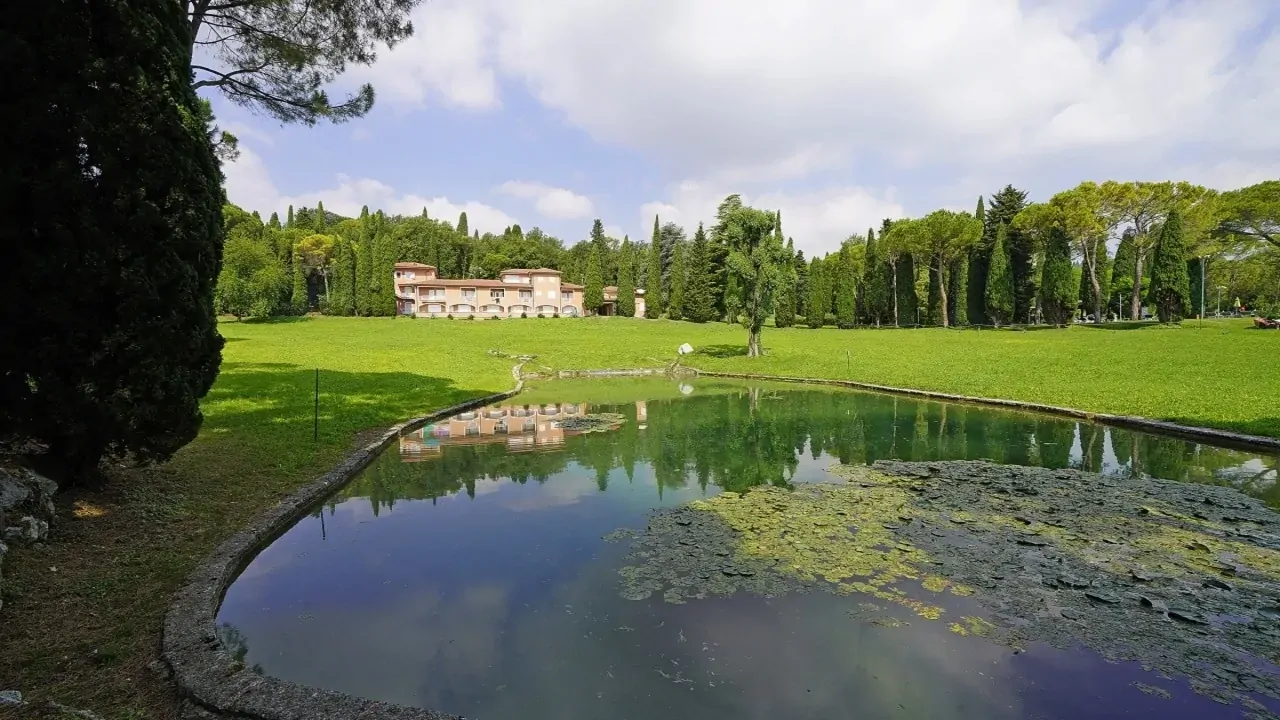 Artificial pond in the park with trees and building in the background