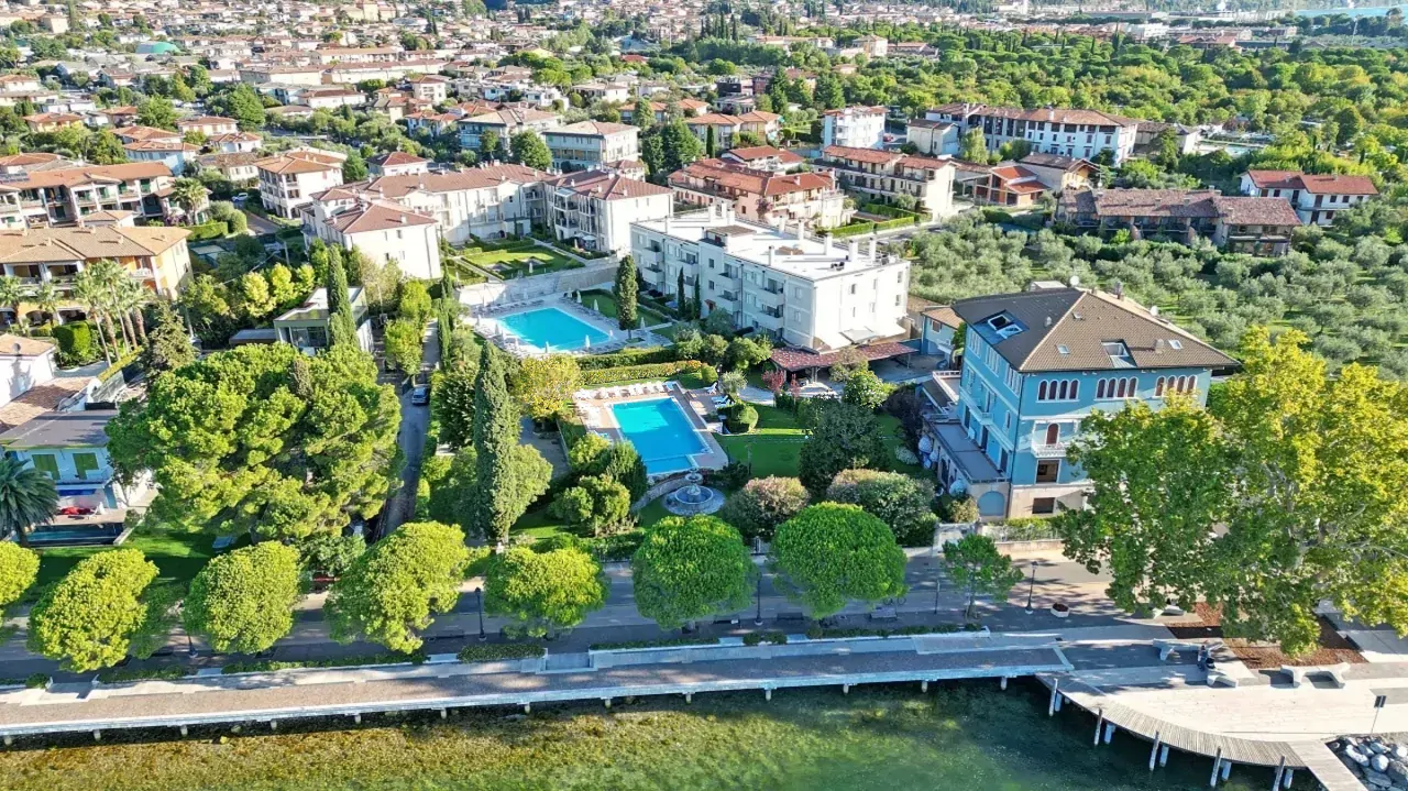 Luftaufnahme der Wohnanlage mit Pool und See im Vordergrund