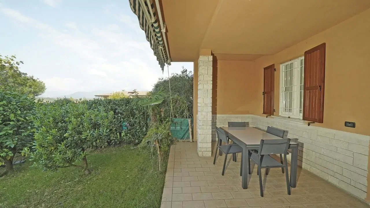 Porch with table and chairs and garden with hedge