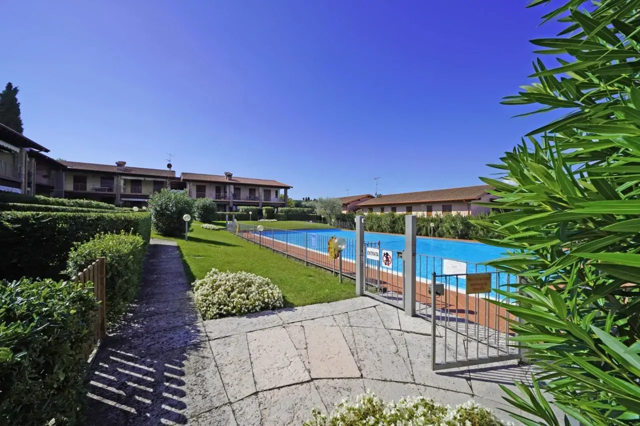 Ingresso alla piscina condominiale con prato e vialetto