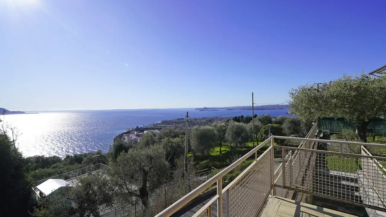 Panoramic view of lake and olive grove from terrace with metal railing