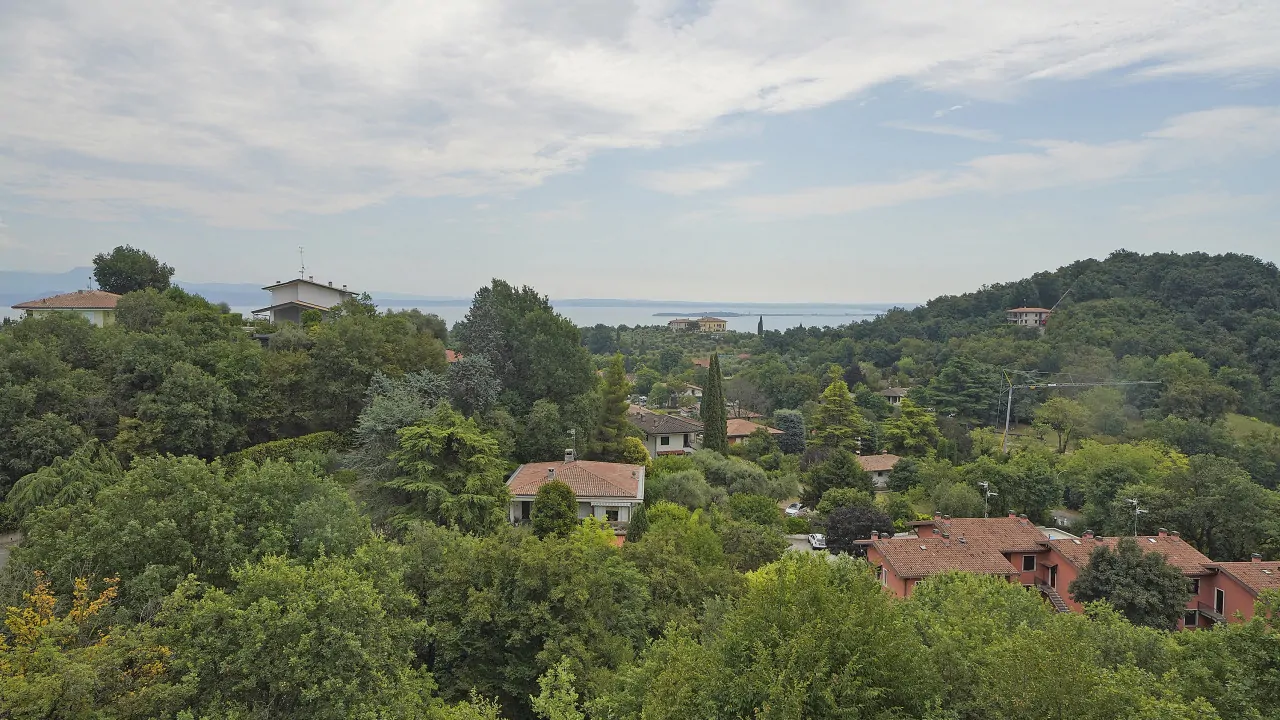 Panoramic view of vegetation, houses and lake in the distance at Soiano del Lago