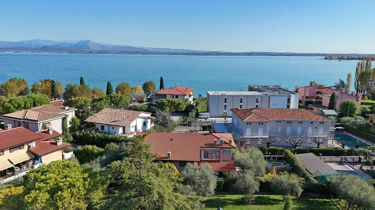 Aerial view of houses with gardens and lake in the background in Sirmione