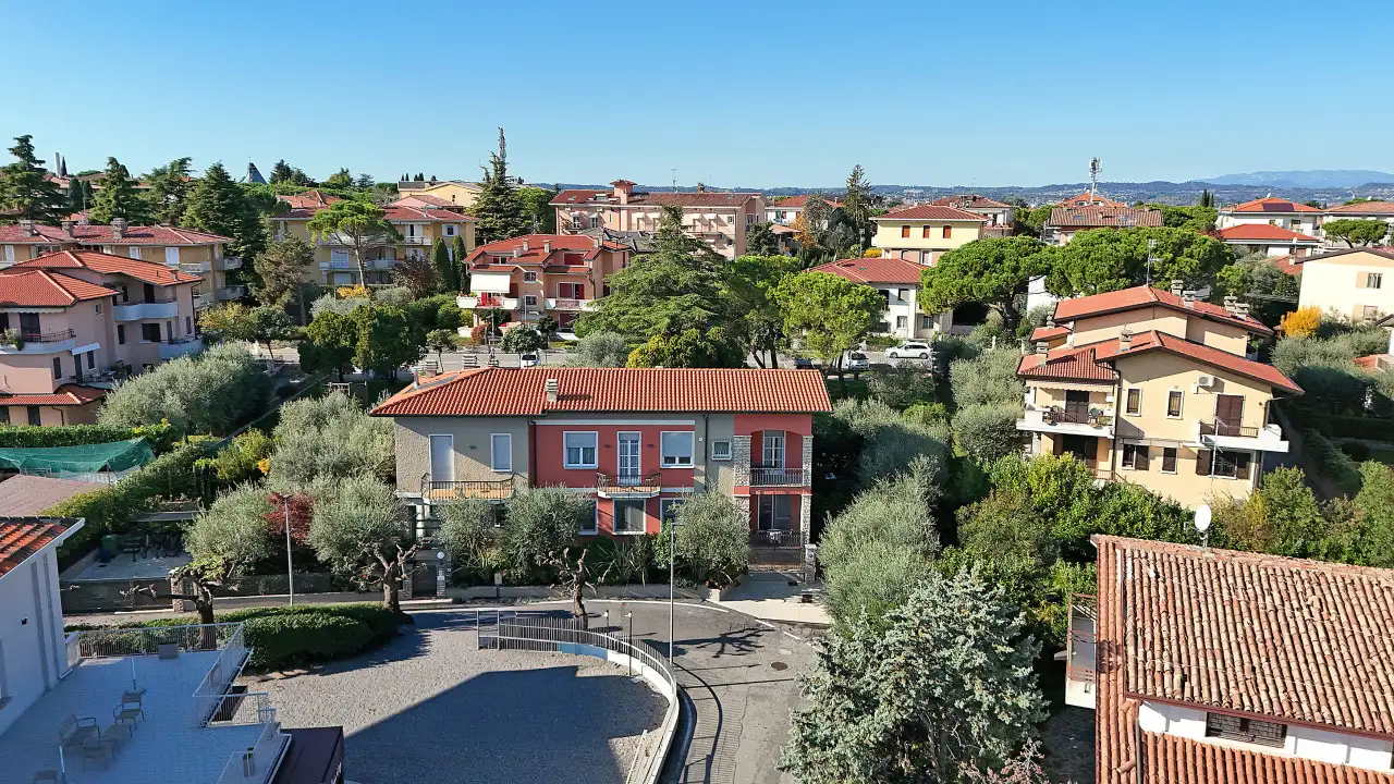 Aerial view of the villa and surrounding houses with trees and streets