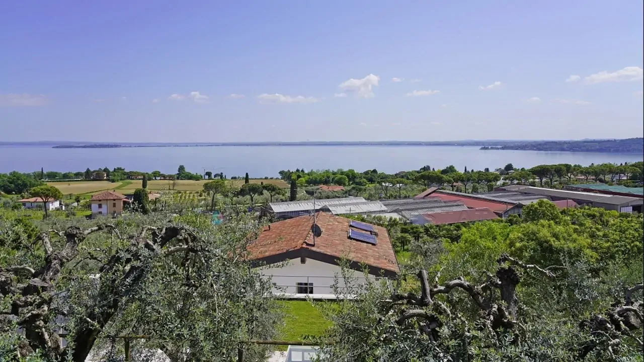 Panoramablick auf den See und die umliegende Landschaft mit Hausdach im Vordergrund