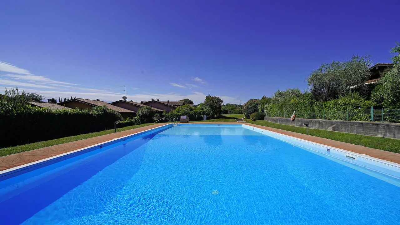 Outdoor rectangular swimming pool with brick border and surrounding lawn