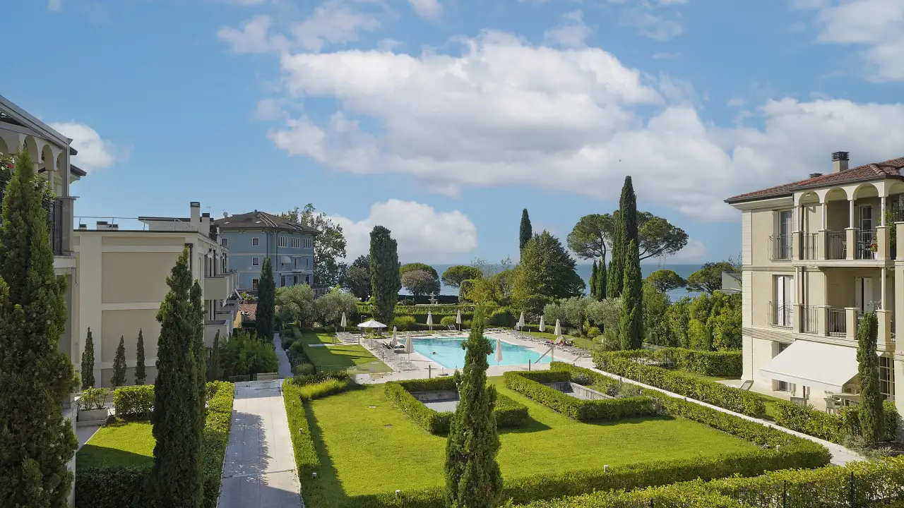 Garden and swimming pool in residence with buildings and cloudy sky