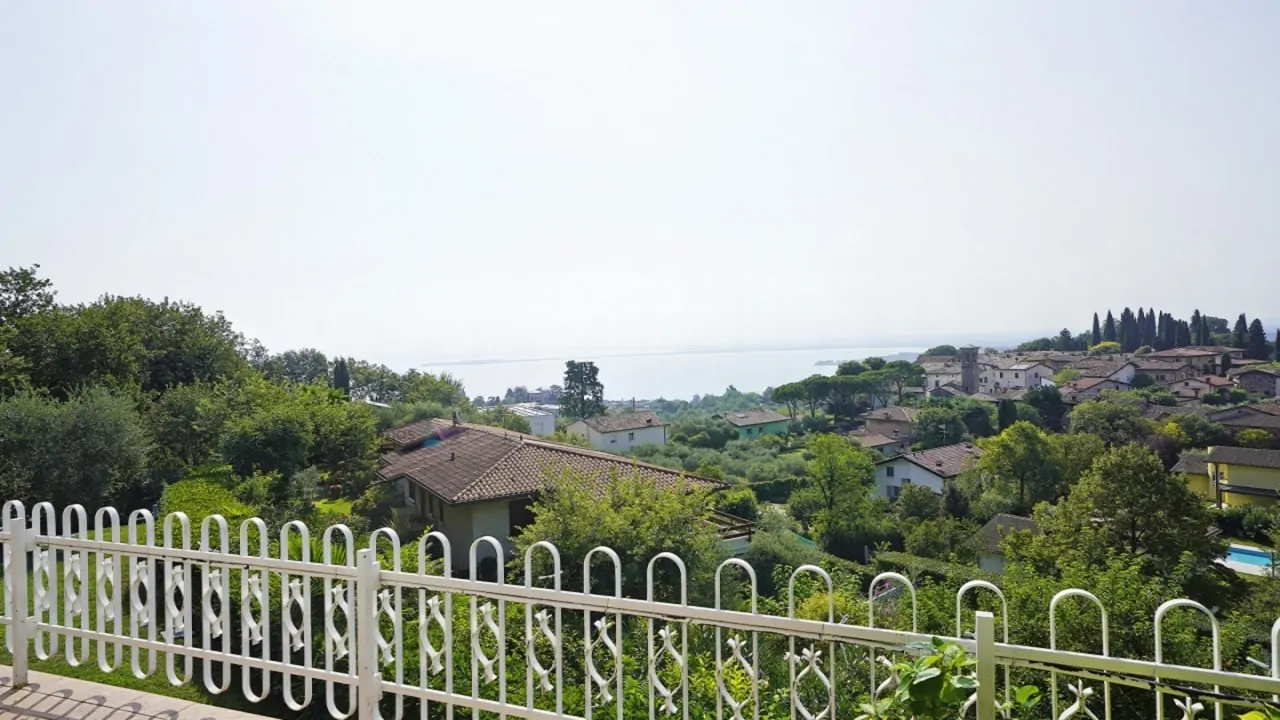 View from balcony with white railing and surrounding vegetation