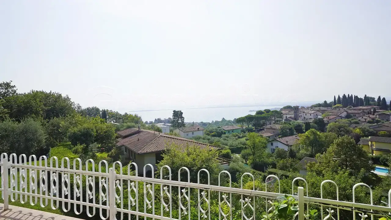 Vista dal balcone con ringhiera bianca e vegetazione circostante