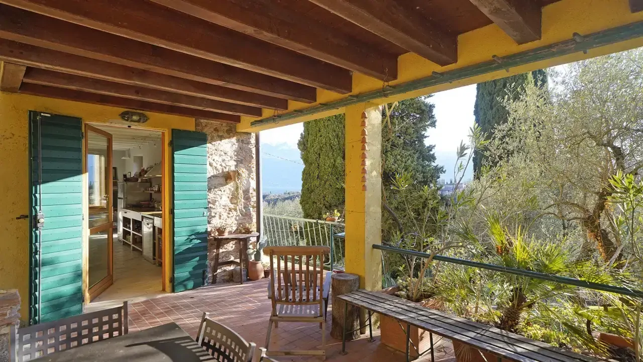 Überdachte Terrasse mit Holzbalken und Blick auf Pflanzen und Bäume