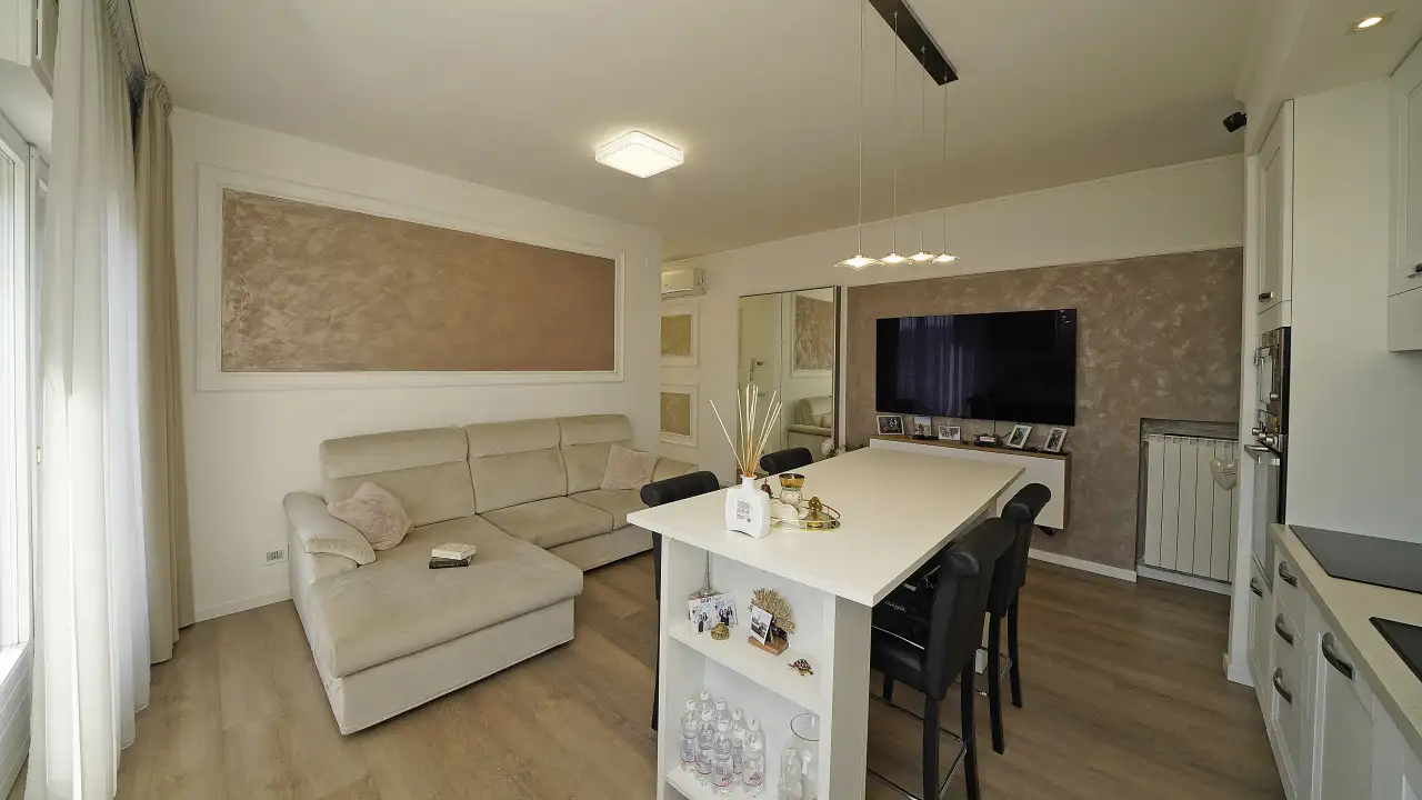 Soggiorno con divano beige e tavolo bianco con sedie nere