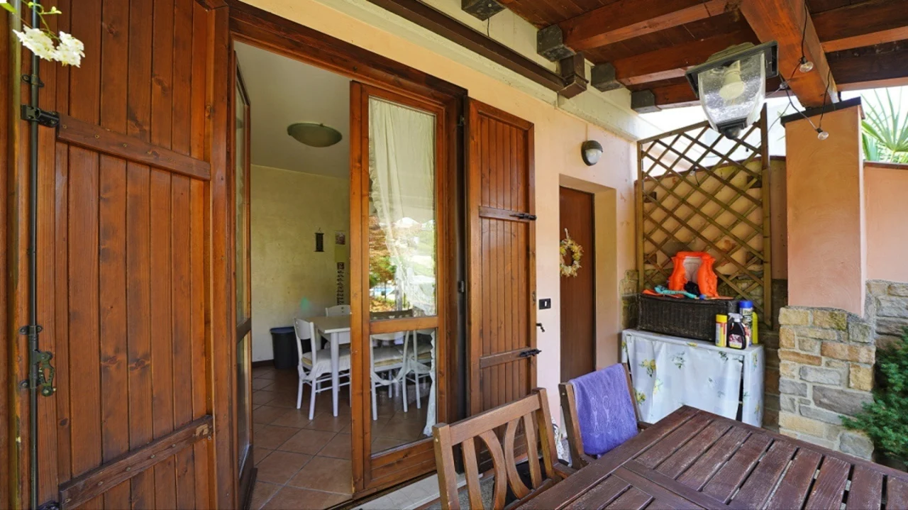 Portico con tavolo in legno e porta finestra con persiane in legno