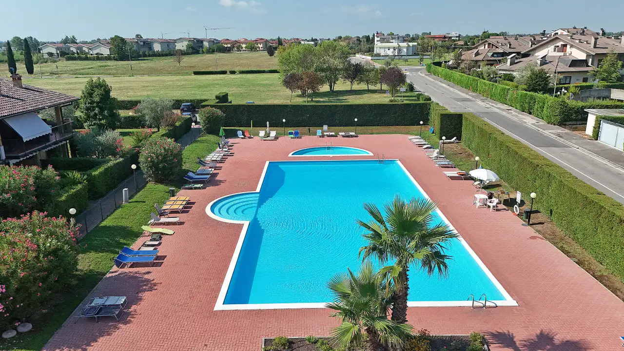 Piscina rettangolare con bordo in mattoni e lettini intorno