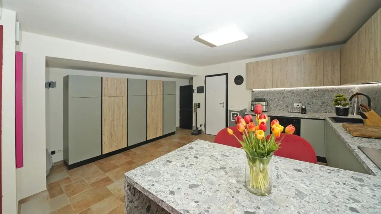 Cucina con mobili in legno chiaro e piano in pietra grigia