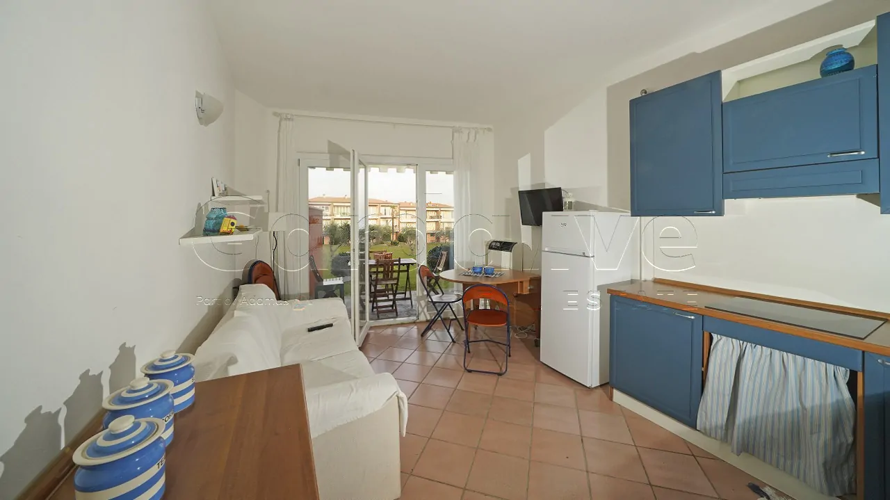 Wohnzimmer mit weißem Sofa und Küche mit blauen Schränken