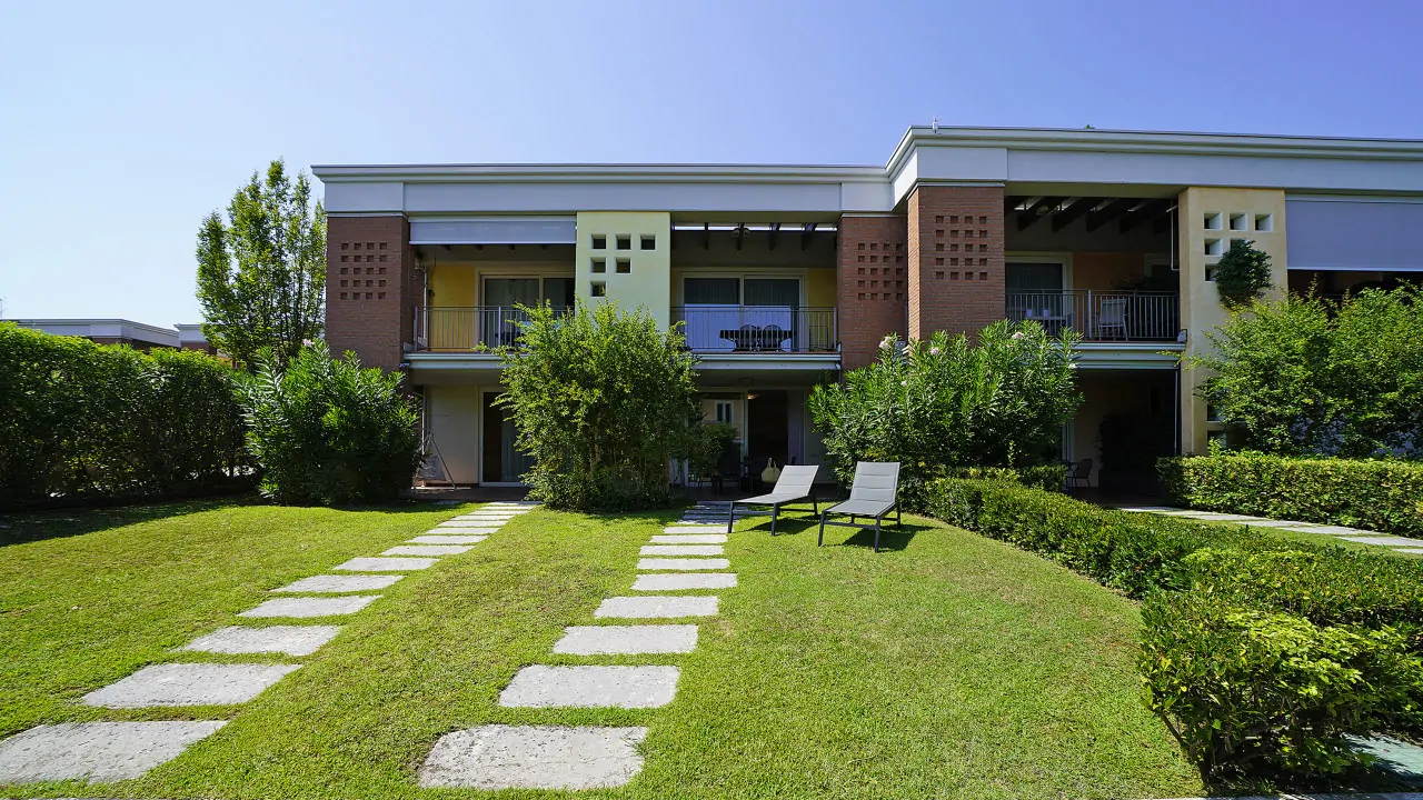 Facciata di residence con giardino e due lettini prendisole