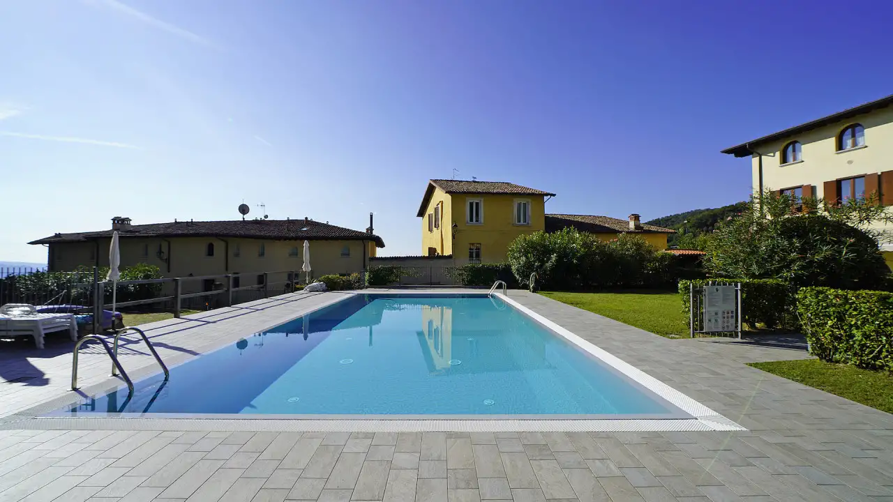Rectangular swimming pool with tiled edge and green lawn