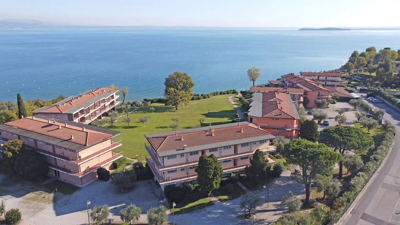 Vista aerea del residence con edifici e lago sullo sfondo a Manerba del Garda