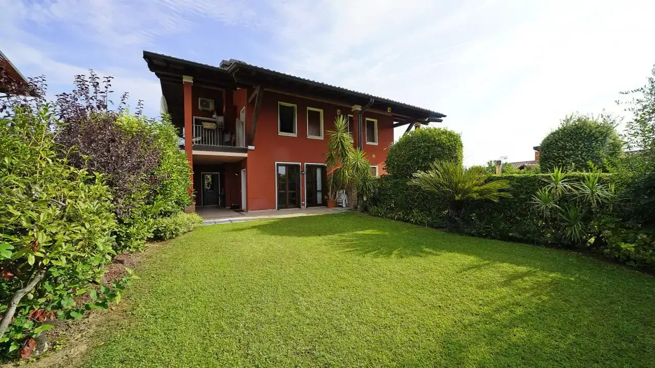 Private garden with lawn and plants in front of two-story red house