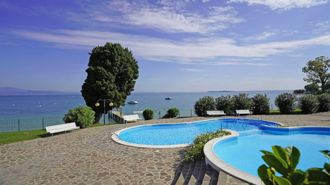 Piscina con bordo bianco e vista lago