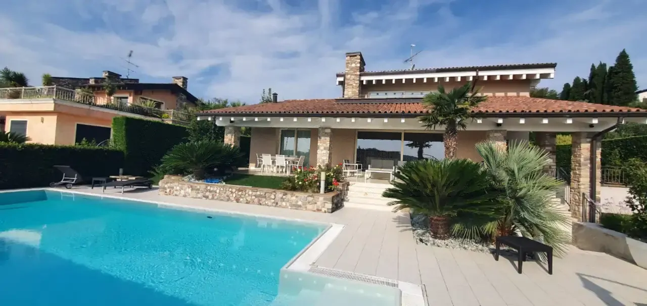 Piscina esterna con villa e terrazza sullo sfondo