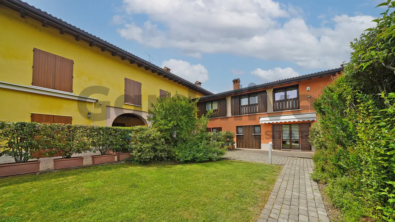 Hof mit Rasen und Kopfsteinpflasterweg zwischen zwei Gebäuden