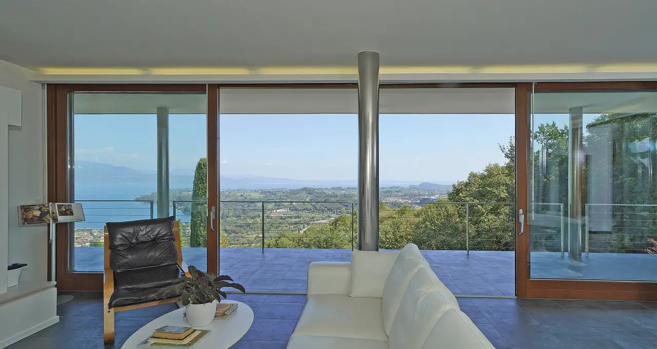 Soggiorno con divano bianco e vetrata panoramica sul terrazzo e paesaggio