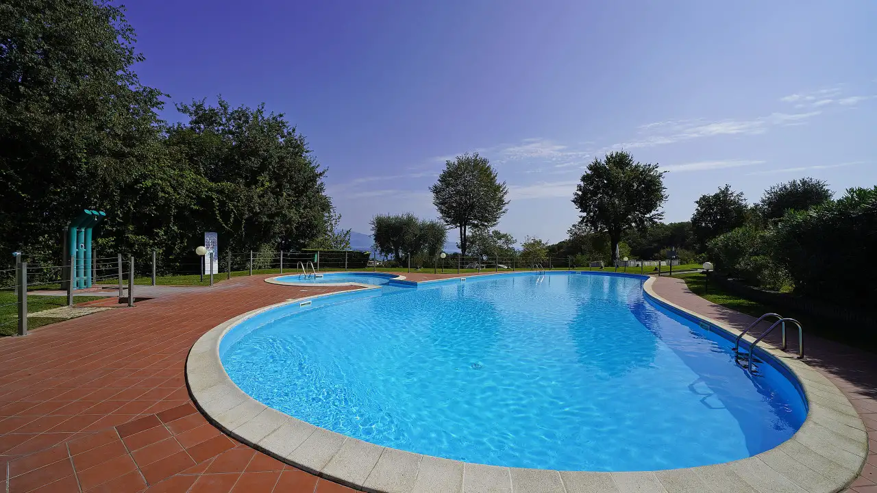 Piscina esterna con bordo in pietra e pavimentazione in cotto