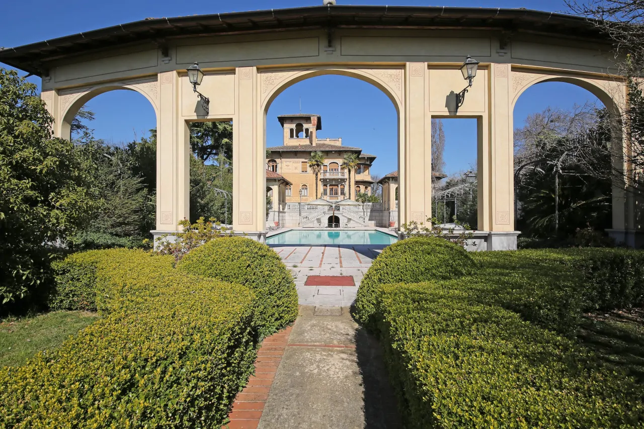 View of the liberty villa through an arch in the garden with pool
