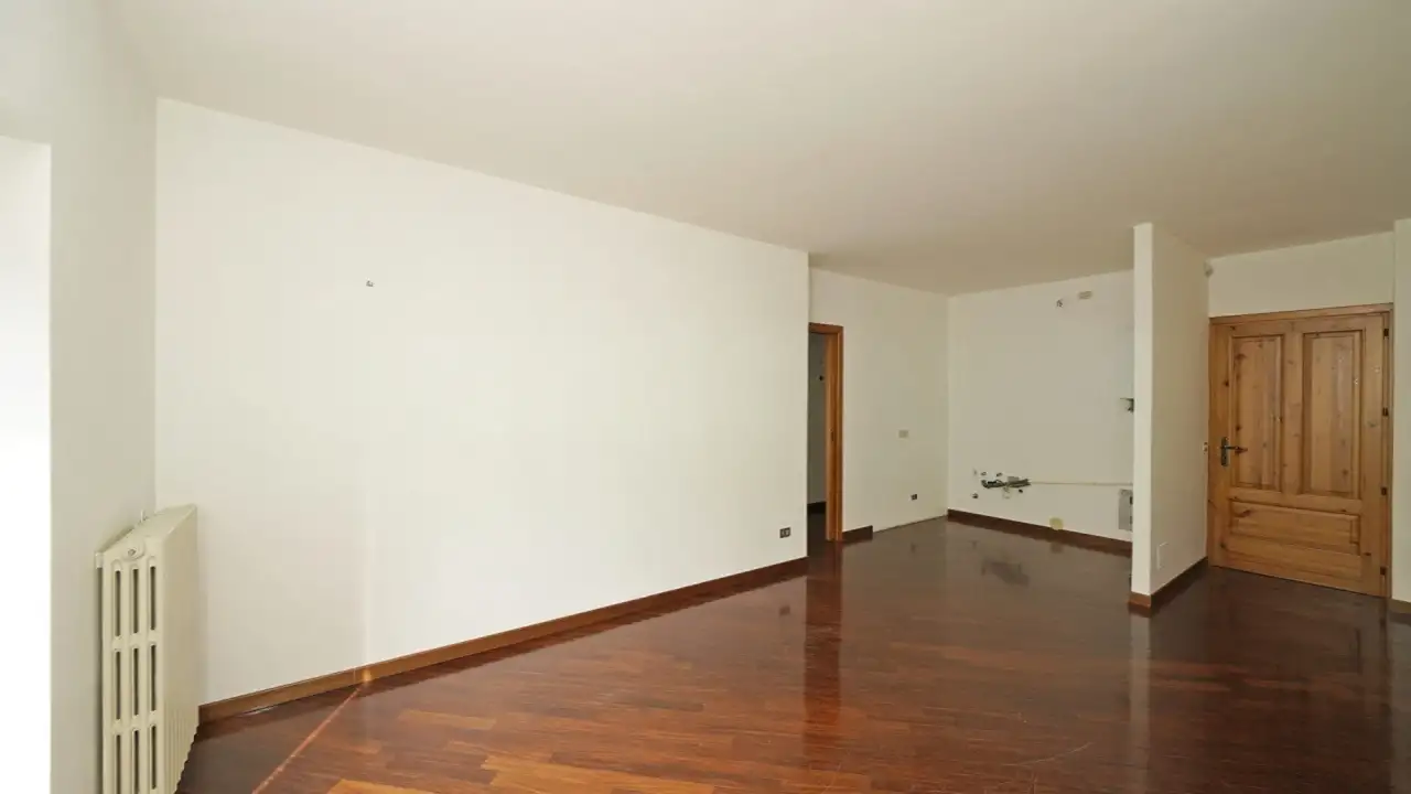 Soggiorno vuoto con pavimento in legno e porta in legno