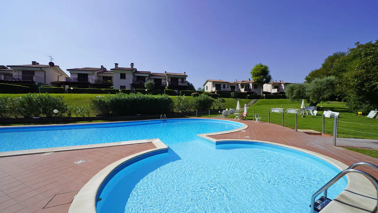 Piscina con bordo piastrellato e prato verde
