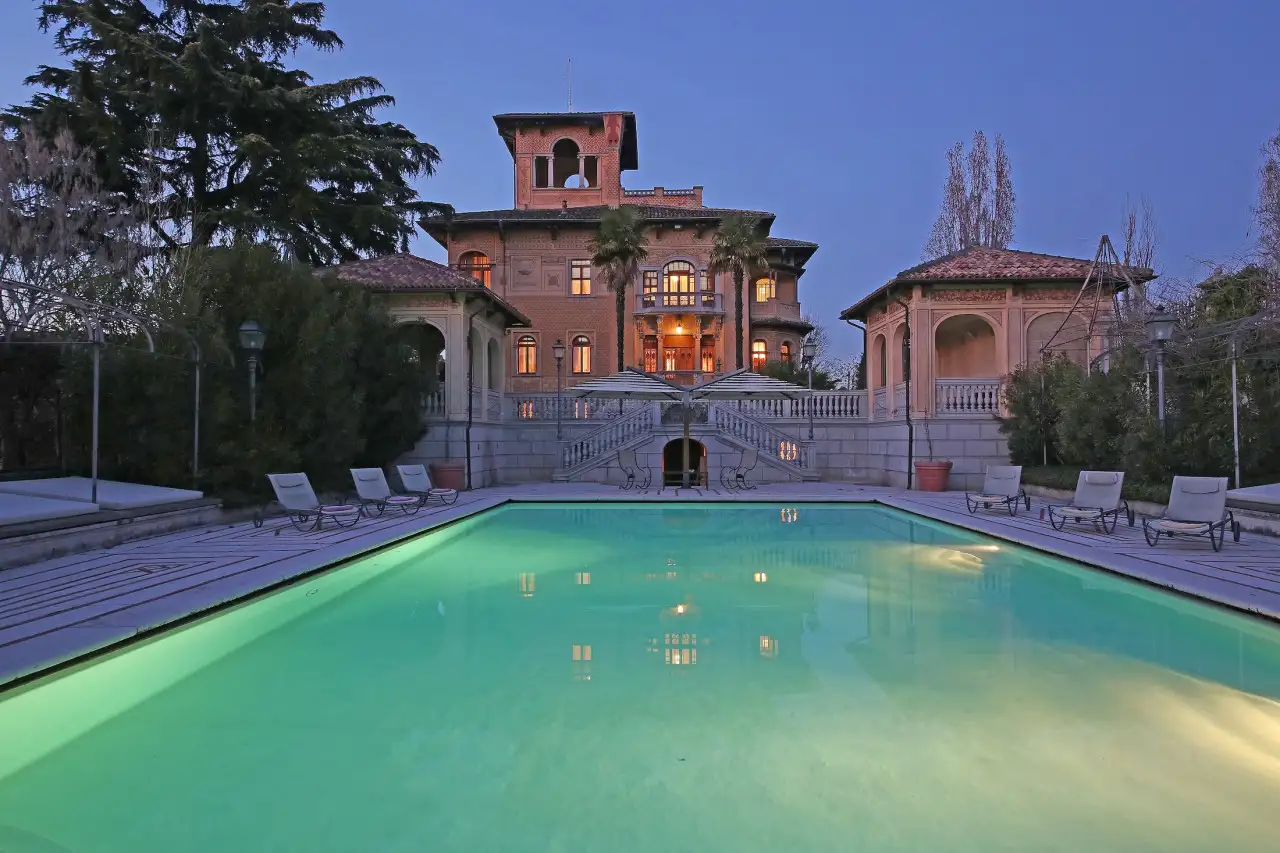 Illuminated swimming pool with liberty villa in the background at dusk