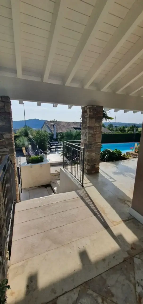 Portico con colonne in pietra e vista su piscina e giardino