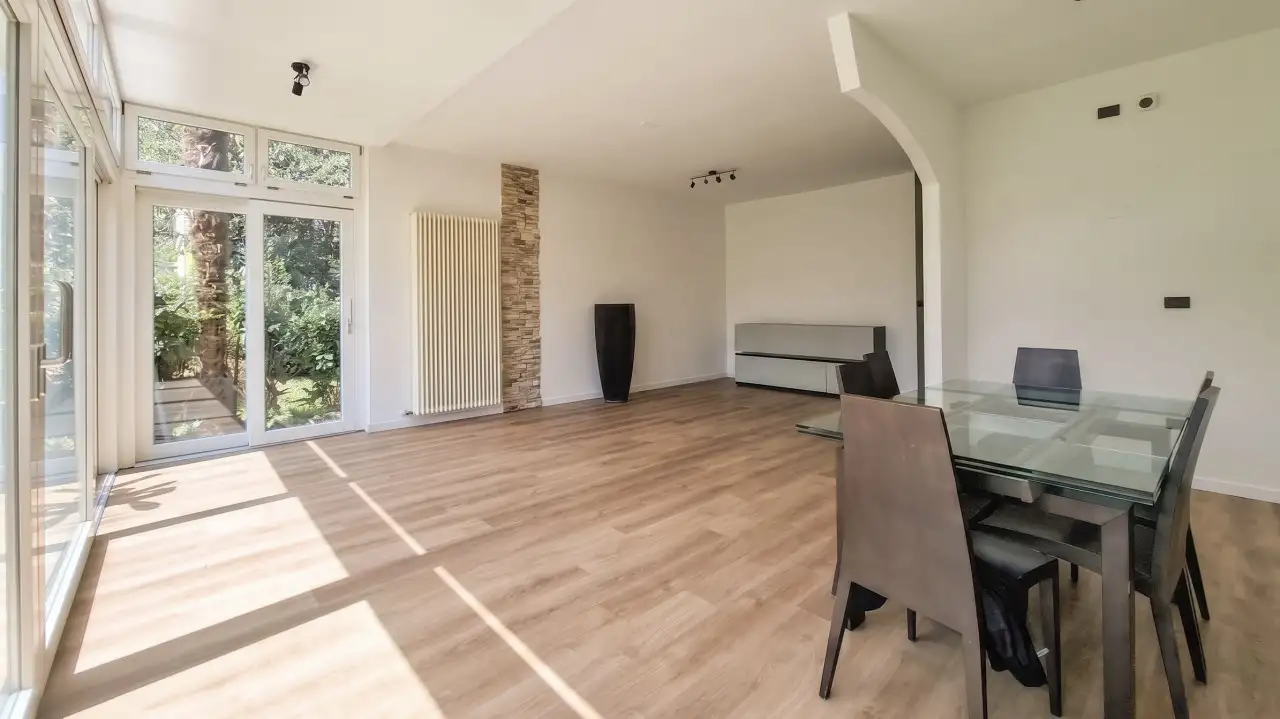 Wohnzimmer mit Glastisch und Terrassentüren zum Garten