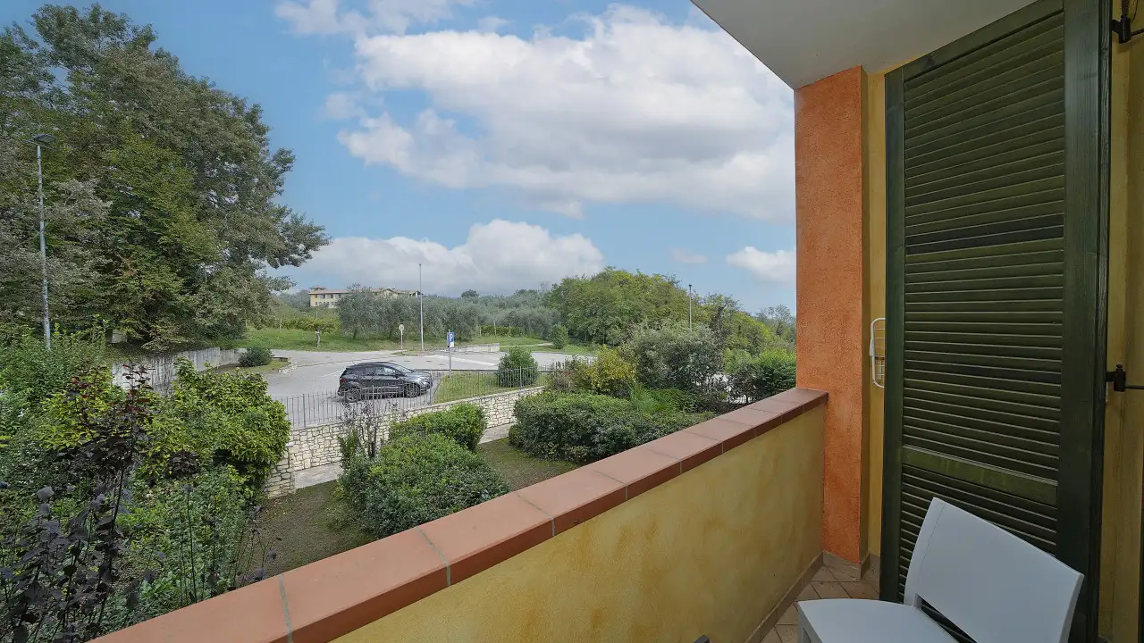 Balcone con ringhiera e sedie con vista su strada e vegetazione