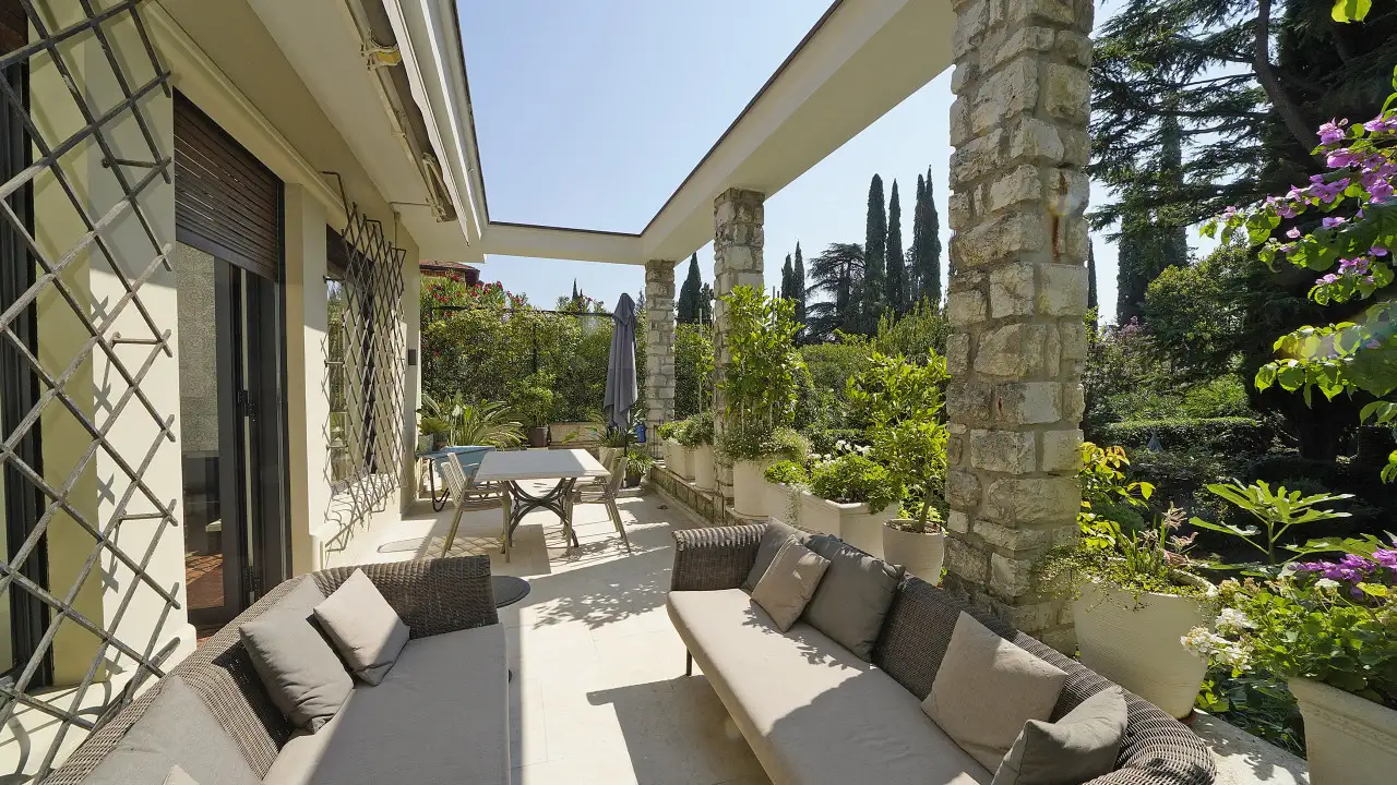 Terrasse mit Sofas und Tisch unter Pergola mit Topfpflanzen