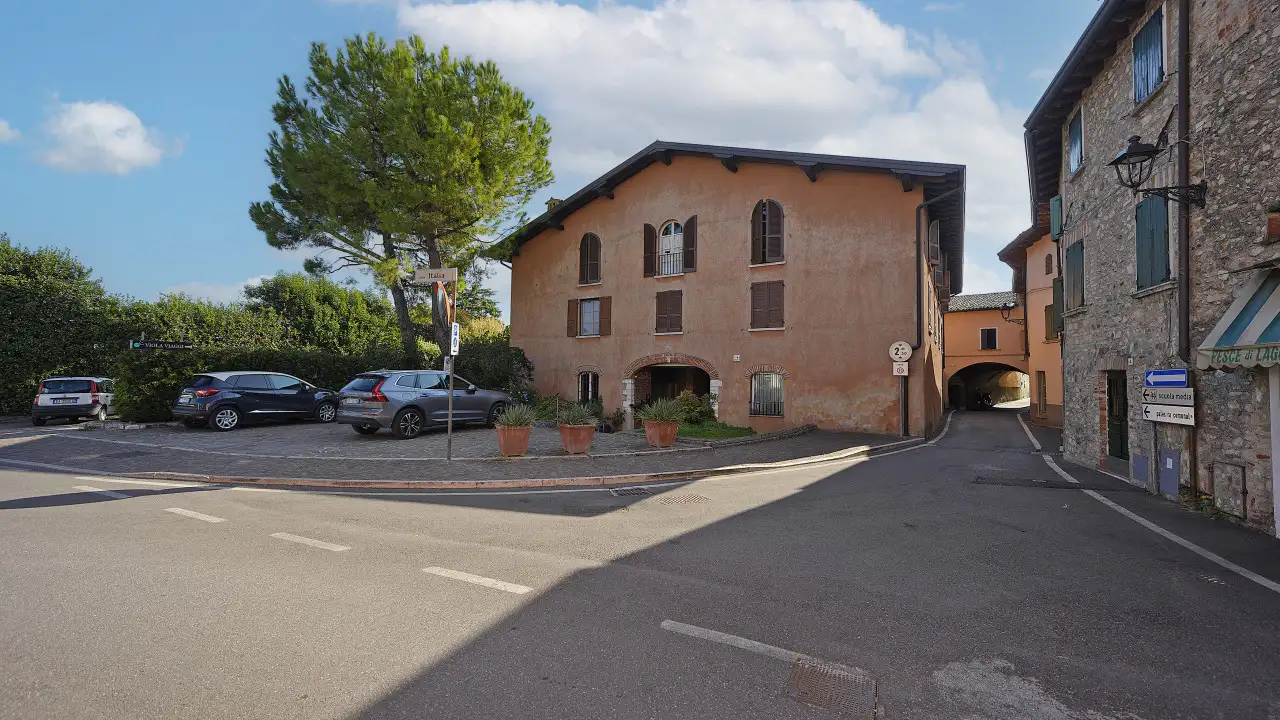Historic building with parking and adjacent street in San Felice del Benaco