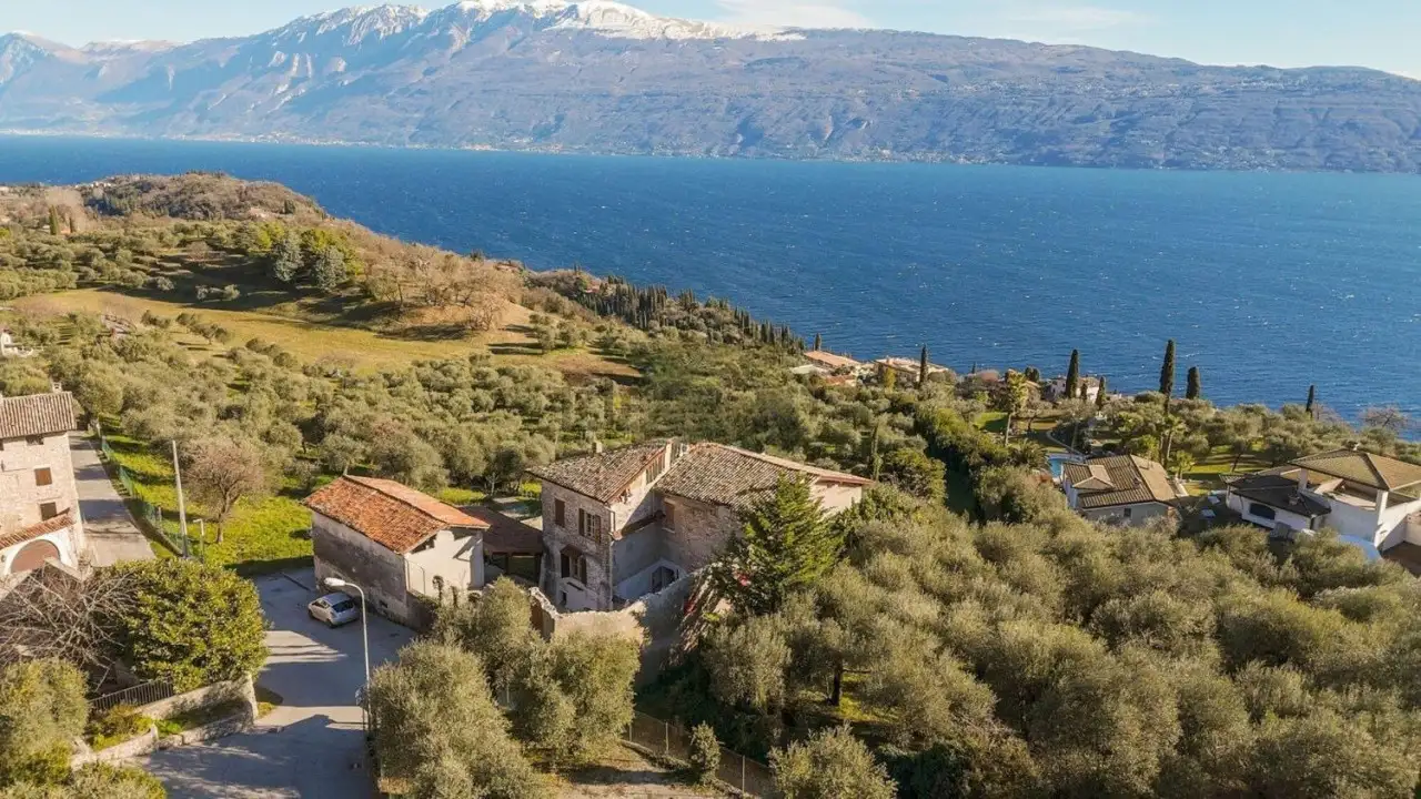 Luftaufnahme des Bauernhauses mit Olivenhain und See im Hintergrund