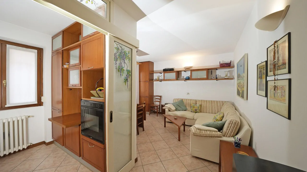 Soggiorno con divano ad angolo e cucina separata da porta scorrevole decorata