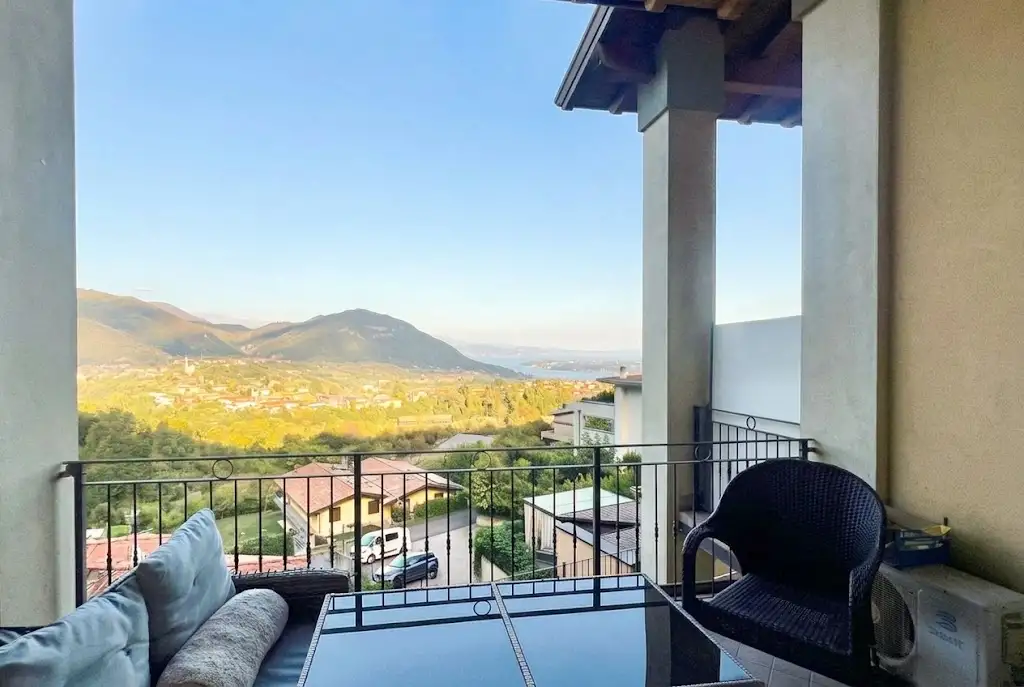 Terrasse mit Tisch und Stühlen und Blick auf Hügel und See