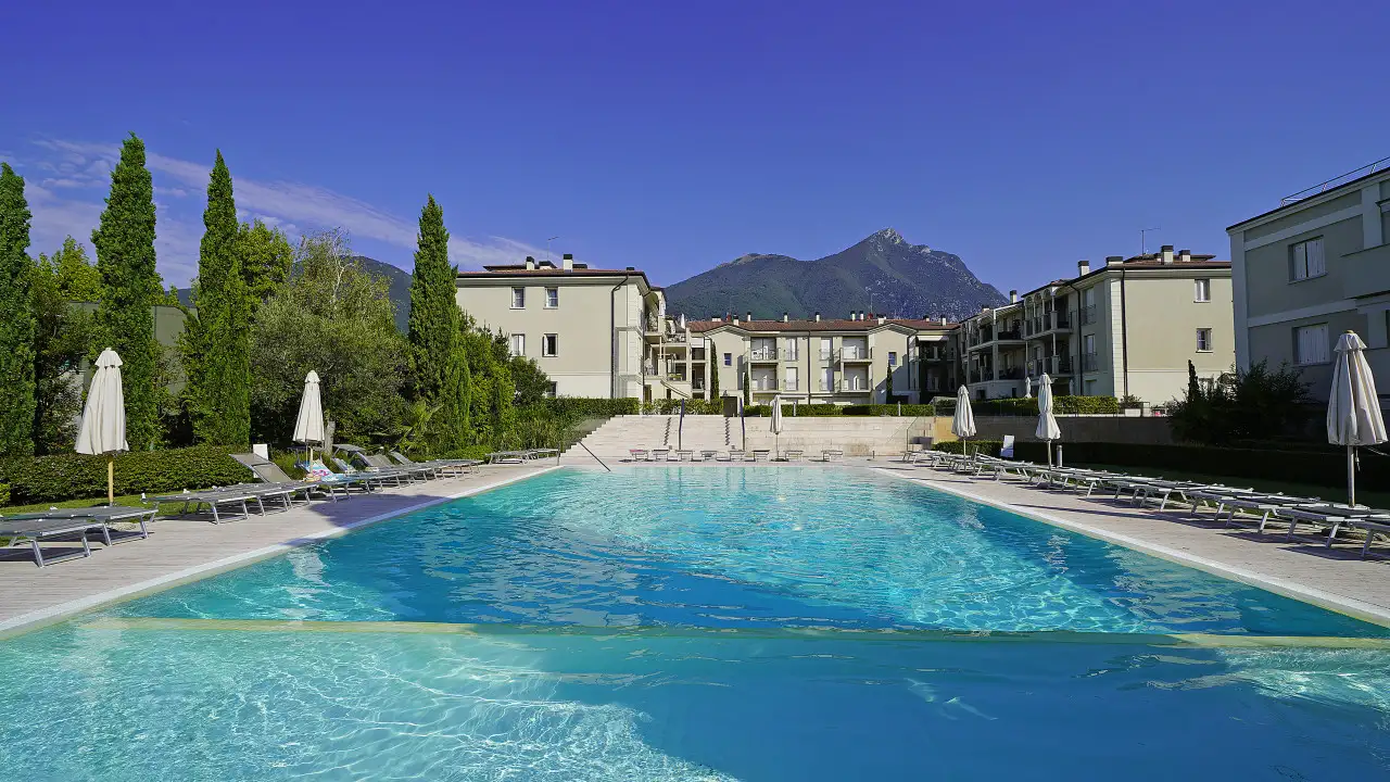 Swimming pool with sunbeds and umbrellas at Corte Fasanella residence in Toscolano Maderno