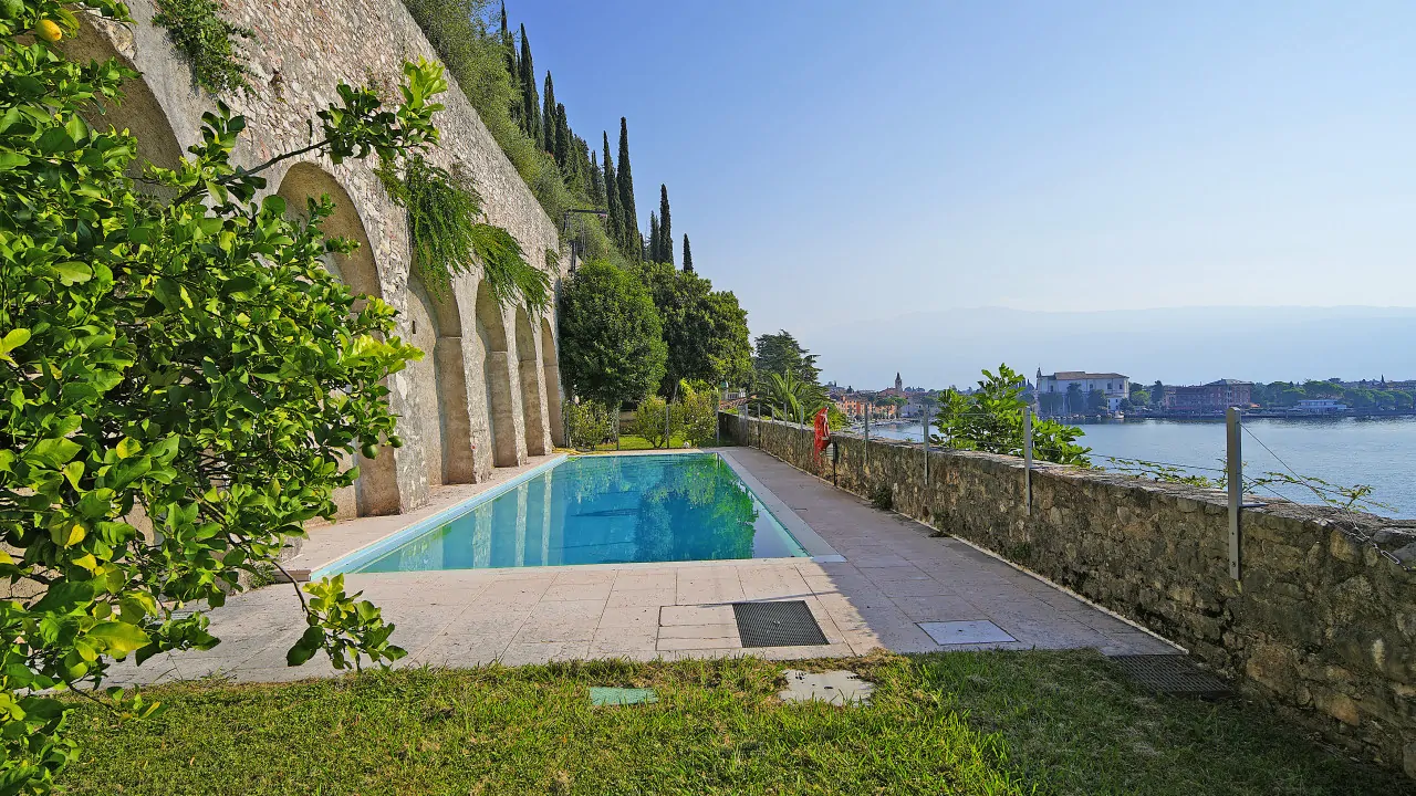 Piscina con muro in pietra e vista lago